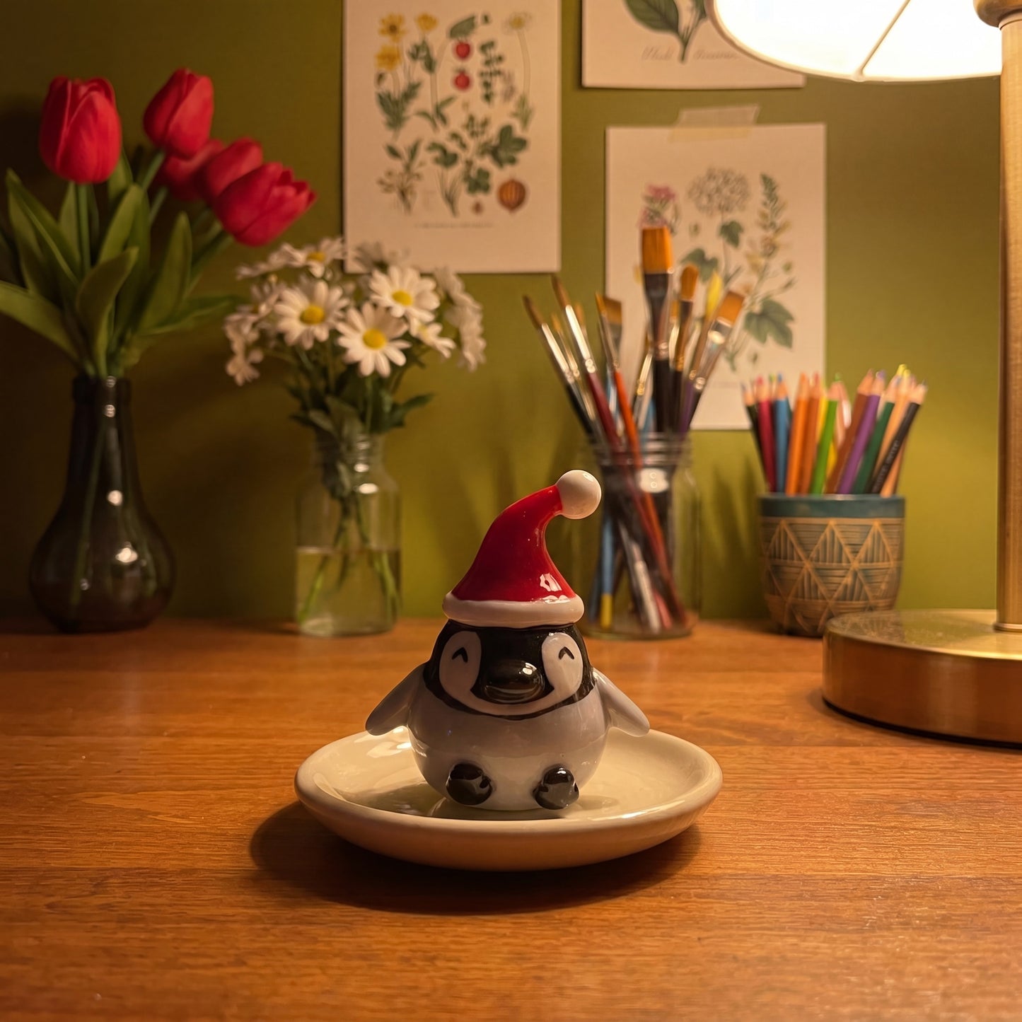Baby Pingoo handmade glossy clay desk pal, in the Moon Kiln studio, evening lamp light