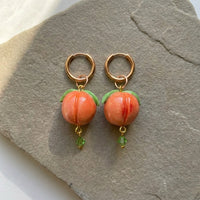 Peaches handmade polymer-clay earrings, the pair on a warm stone surface