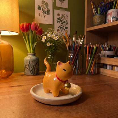Ginger kitty handmade glossy clay desk pal, in the Moon Kiln studio, evening lamp light