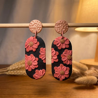 Cherry Blossoms handmade polymer-clay earrings, displayed on a stand in warm evening light