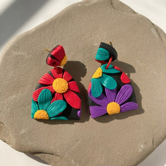 Chroma Flora handmade polymer-clay earrings, the pair on a warm stone surface