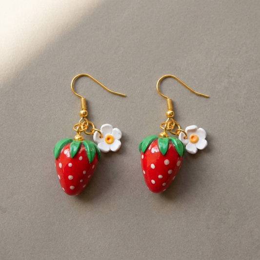 Strawberries handmade polymer-clay earrings, the pair on a warm stone surface