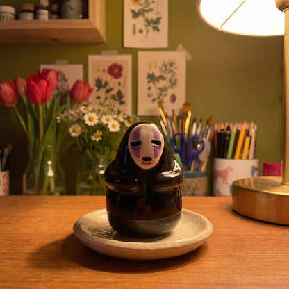 Masked Spirit handmade glossy clay desk pal, in the Moon Kiln studio, evening lamp light