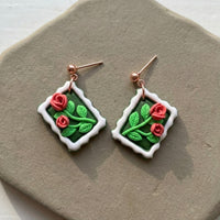 Roses Stamp handmade polymer-clay earrings, the pair on a warm stone surface