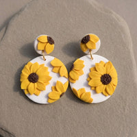 Sunflower Dangles handmade polymer-clay earrings, the pair on a warm stone surface