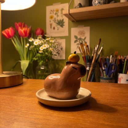 Capybara handmade glossy clay desk pal, in the Moon Kiln studio, evening lamp light