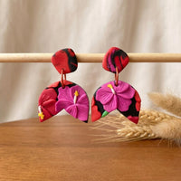 Hibiscus Jungle handmade polymer-clay earrings, displayed on a stand in soft daylight