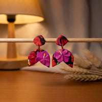 Hibiscus Jungle handmade polymer-clay earrings, displayed on a stand in warm evening light