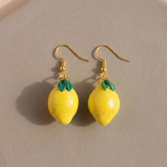 Lemonita handmade polymer-clay earrings, the pair on a warm stone surface