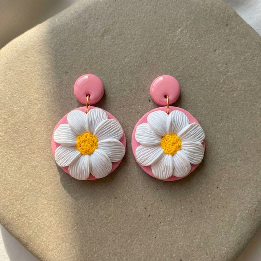 Daisy Lover handmade polymer-clay earrings, the pair on a warm stone surface