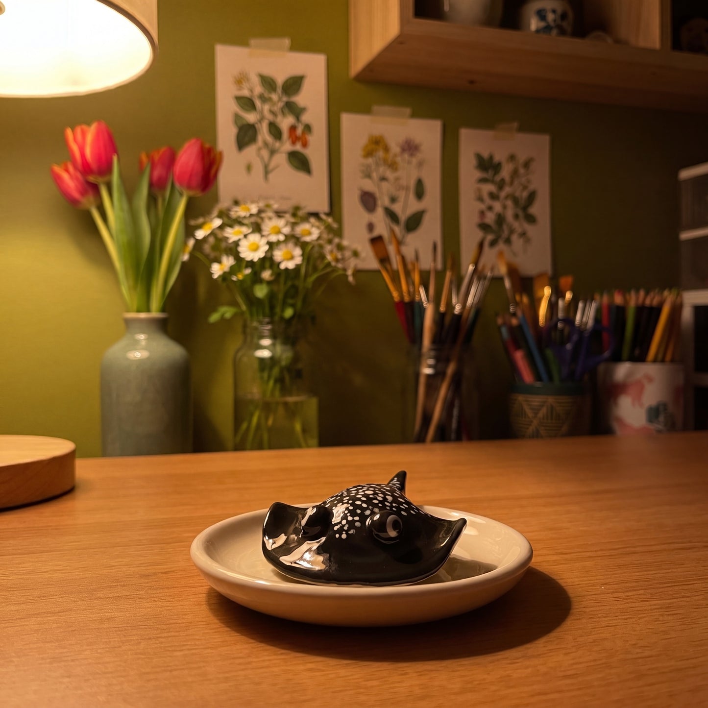 Stinger Ray handmade glossy clay desk pal, in the Moon Kiln studio, evening lamp light