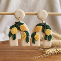Lemon Botanica handmade polymer-clay earrings, displayed on a stand in soft daylight