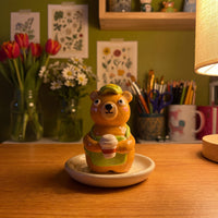 Bearista handmade glossy clay desk pal, in the Moon Kiln studio, evening lamp light