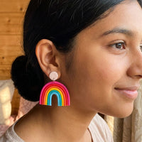 Rainbow handmade polymer-clay earrings, worn on the ear