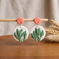 Just Leaves handmade polymer-clay earrings, displayed on a stand in soft daylight