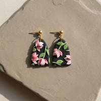 Roseate Drops handmade polymer-clay earrings, the pair on a warm stone surface