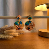Tropical Daylily handmade polymer-clay earrings, displayed on a stand in warm evening light