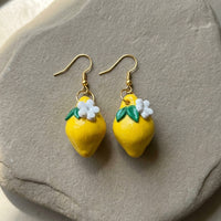 Lemonita handmade polymer-clay earrings, the pair on a warm stone surface