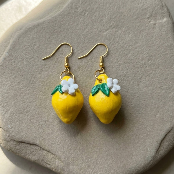 Lemonita handmade polymer-clay earrings, the pair on a warm stone surface
