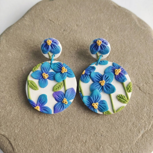 Himalayan Poppies handmade polymer-clay earrings, the pair on a warm stone surface