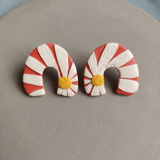 Daisy Bend handmade polymer-clay earrings, the pair on a warm stone surface