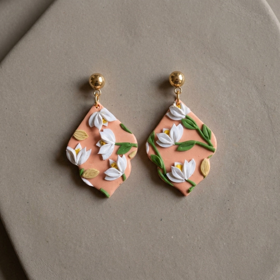 Sunset Bouquet handmade polymer-clay earrings, the pair on a warm stone surface