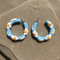 Daisy Blue Hoops handmade polymer-clay earrings, the pair on a warm stone surface