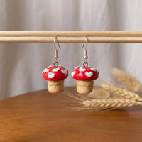 Shroom hearts handmade polymer-clay earrings, displayed on a stand in soft daylight