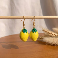 Lemonita handmade polymer-clay earrings, displayed on a stand in soft daylight