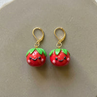 Tomatoes handmade polymer-clay earrings, the pair on a warm stone surface