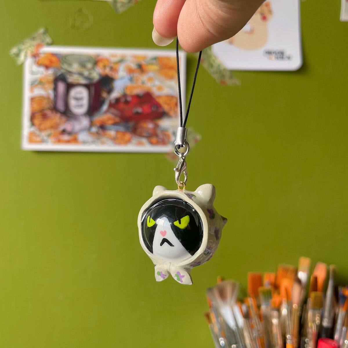 Grumpy Babushka polymer clay charm, round white cat face with grumpy green eyes and tiny ears, glossy finish, on black cord
