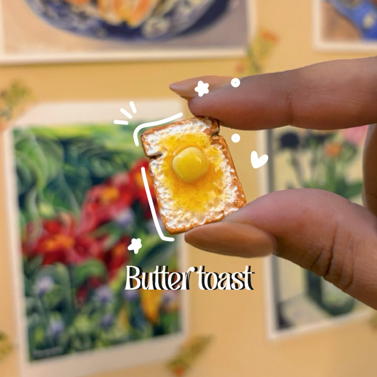 Butter toast handmade polymer clay keychain, miniature golden toast with melted butter pool, held between thumb and finger, glossy glaze