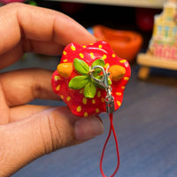 Sir Berryface handmade polymer clay charm, side angle showing glossy orange fox head with red spotted strawberry hat