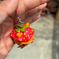 Sir Berryface handmade polymer clay charm, lifestyle hanging shot showing fox with strawberry hat and checked gingham bow