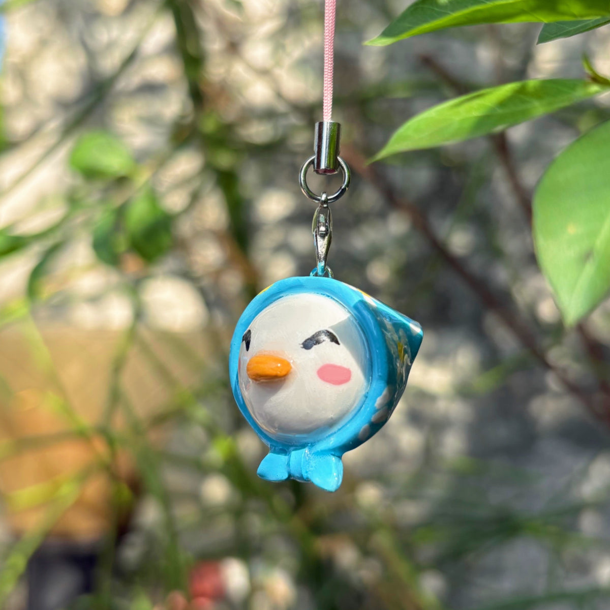 Blue Hooded Bird handmade polymer clay charm, round white bird face with blue hoodie, orange beak, and rosy cheeks, on silver cord