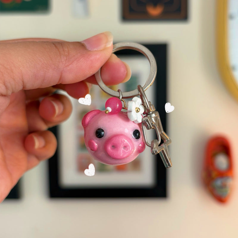 Piggy handmade polymer clay keychain, glossy pink pig head with snout and white daisy on ear, on silver key ring with clip
