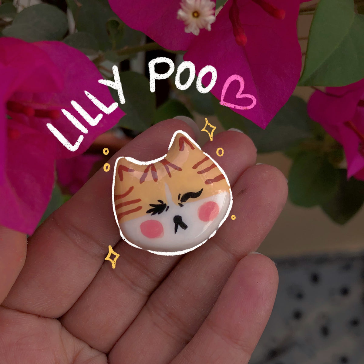 Lilly Poo handmade polymer clay fridge magnet, glossy orange tabby cat face with rosy cheeks and grumpy expression, held in palm