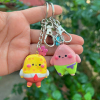 Pink Starfish handmade polymer clay keychain, in-hand scale showing glossy pink starfish character with green shorts detail