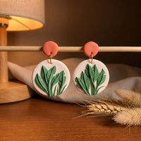 Just Leaves handmade polymer-clay earrings, displayed on a stand in warm evening light