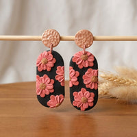 Cherry Blossoms handmade polymer-clay earrings, displayed on a stand in soft daylight