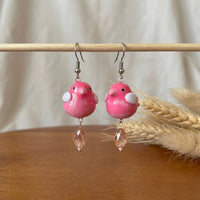 Love at first chirp earrings handmade polymer-clay earrings, displayed on a stand in soft daylight