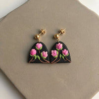 Magnolia handmade polymer-clay earrings, the pair on a warm stone surface