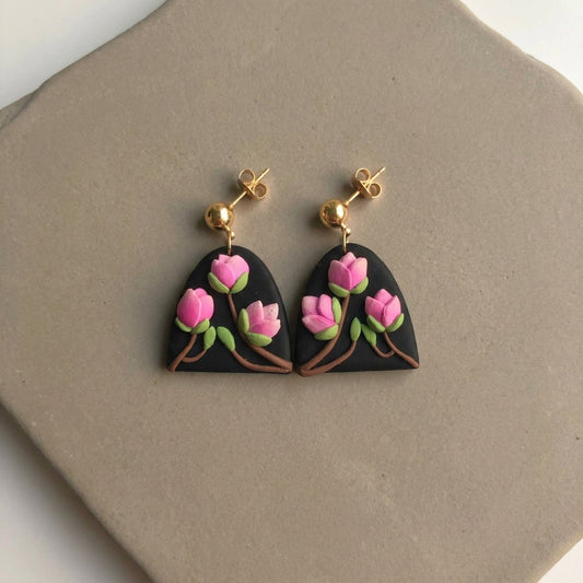 Magnolia handmade polymer-clay earrings, the pair on a warm stone surface
