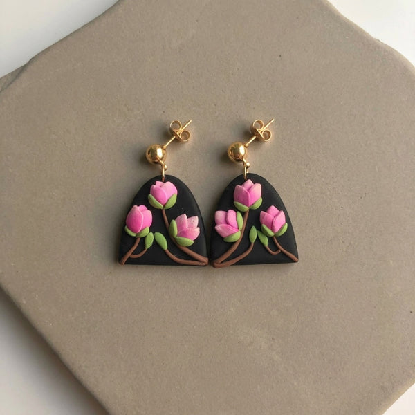 Magnolia handmade polymer-clay earrings, the pair on a warm stone surface