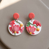 Pink Tipped Lotus handmade polymer-clay earrings, the pair on a warm stone surface
