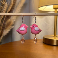 Love at first chirp earrings handmade polymer-clay earrings, displayed on a stand in warm evening light