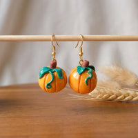 Pumpkiln handmade polymer-clay earrings, displayed on a stand in soft daylight