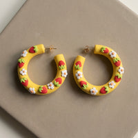 Strawberry Hoops handmade polymer-clay earrings, the pair on a warm stone surface