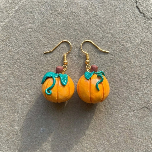 Pumpkiln handmade polymer-clay earrings, the pair on a warm stone surface