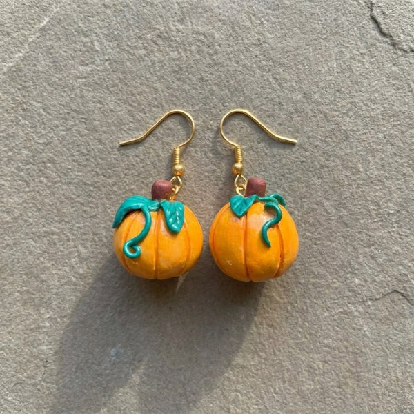 Pumpkiln handmade polymer-clay earrings, the pair on a warm stone surface